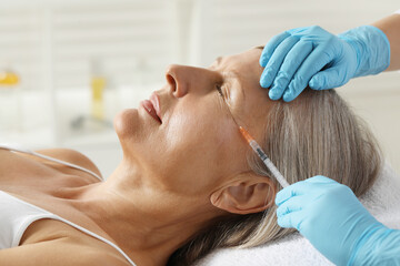 Doctor giving facial injection to senior woman in clinic, closeup. Cosmetic surgery