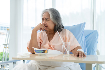 An elderly Asian patient has lost his appetite and is worried about her sickness. - obrazy, fototapety, plakaty