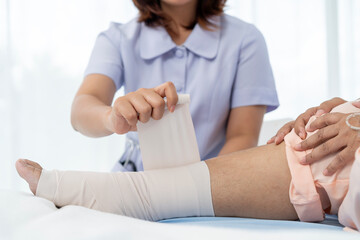 Close-up photo of an Elderly Asian patient admitted to hospital A nurse cares for a patient's injured leg bandage.