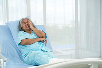 An elderly female patient is holding her head in pain. from acute pain from a cerebral ischemic stroke