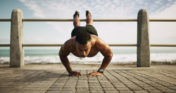 Man, push up and exercise at the beach for fitness or training outdoor for challenge in workout goals. Healthy, person and balance on fence at ocean for health, wellness and growth in arms muscle