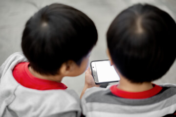 two asian brother playing smart phone togehter