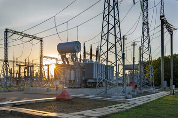 High voltage electrical transformer at sunset.