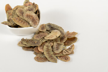 Senna alexandrina pods. Cassia senna, with depurative and detoxifying properties in a white ceramic bowl isolated on a white background.
