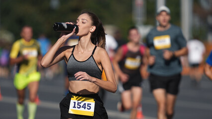 Woman athlete drinking water bottle. Thirsty people run long distance. Girl sport runner work out....