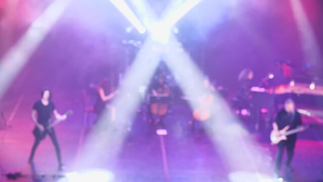 Rock band and symphony orchestra on stage playing world hits of rock music. Front view. Soft Focus. Light and smoke accompaniment of the show. Featuring band, violin, cello, piano, guitar, bass, drum