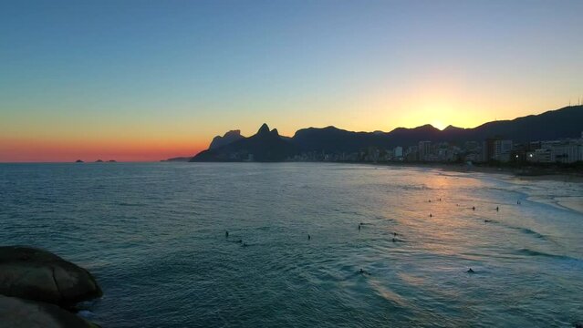 Aerial Forward Shot Of People Swimming In Sea Near City And Mountains Against Sky At Sunset - Rio de Janeiro, Brazil