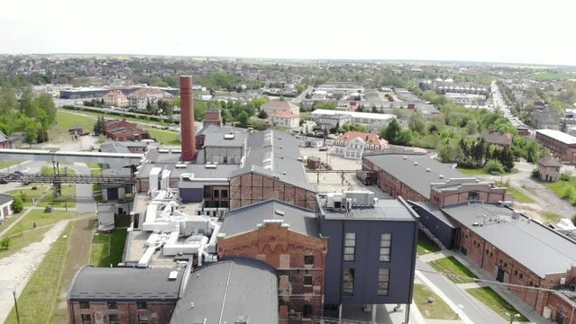 Aerial slow orbit shot of the Arche Hotel Żnin inside old sugar factory in Poland. The tall chimney of the factory is a famous landmark, rising above the surrounding landscape