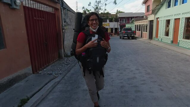 Hispanic woman with two heavy back packs dances, twirls on HDN street