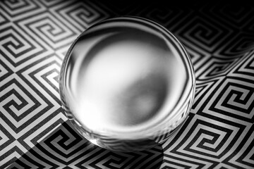 Glass sphere on a geometric black and white pattern, copy space