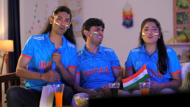 Indian friends wearing Indian cricket jerseys watching a cricket match - disappointed fans  emotional reaction  angry cricket fans  sports concept. Cricket world cup series: fans watching cricket m...