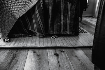 Toddler Hands Peeking Out Underneath Blanket Fort in Family Room