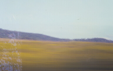 Double Film Exposure of a hay field with mountains in background