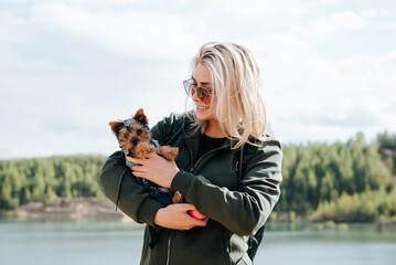 Portrait of a happy, smiling young woman holding a pet in her arms outdoors