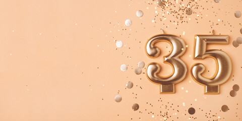 35 years celebration. Greeting banner. Gold candles in the form of number thirty five on peach background with confetti.