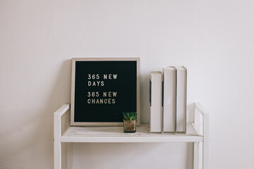 Letter board with text 365 New Days, 365 New Chances on bookshelf. Motivation quote, new year...