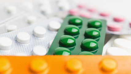 Pile of various pills and tablets in a blister pack on white background, healthcare and medicine concept