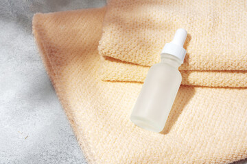 Cosmetic oil bottles and towels on gray background