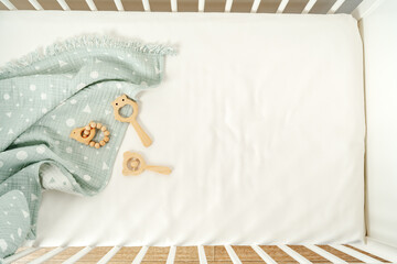 Toys and muslin soft blanket in baby bed close up