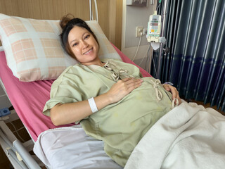 happy pregnant woman patient is resting on bed in hospital