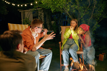 Teenager having fun at bonfire telling horror stories spending time at campsite