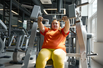 Beautiful young chubby woman working out on fitness gym equipment