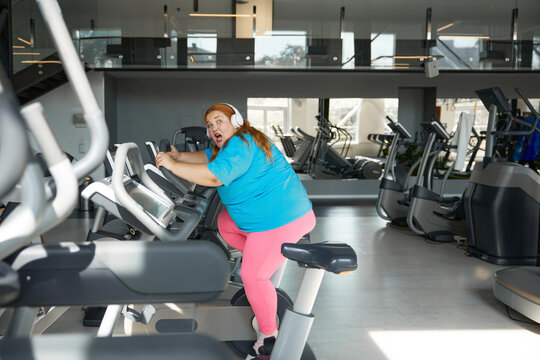 Crazy motivated overweight woman riding fast on stationary bike