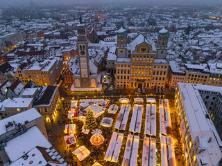 Romantischer Blick auf den Weihnachtsmarkt in Augsburg an einem verschneiten Abend im Dezember
