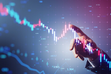 Close up of man hand pointing at glowing downward candlestick forex chart on blurry background....