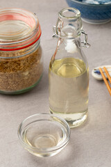 Glass bottle and cup with brown rice vinegar close up