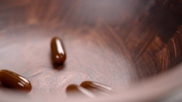 Hand takes sunflower lecithin gel capsules from a dark wooden container. Natural supplements. Close up