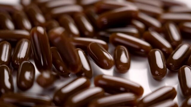 Soft gel capsules with sunflower lecithin falling in slow motion. Dietary supplements. Rotation. Close up