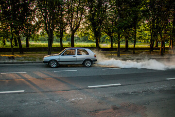 A lot of smoke comes out of the exhaust pipe of a gray car