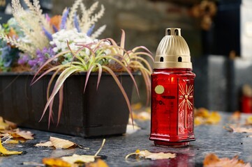 All Souls' Day. A lit candle on the grave. Background with cemetery. Autumn time and holidays. Soulstice - remembrance of the dead - Halloween holiday.