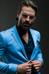 attractive high class man with glasses unbuttoning blue suit