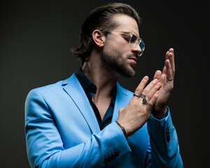 unshaved cool man with glasses looking to side while rubbing palms