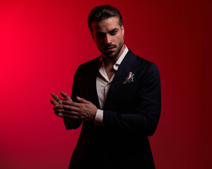 sensual elegant businessman in suit with open collar shirt rubbing palms