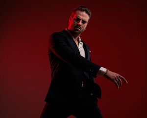cool fashion man in suit with open collar shirt holding arms in fashion pose