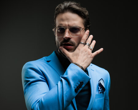 sensual high class man with glasses touching lips in a seductive way