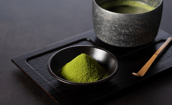 Matcha powder and green tea on dark background.