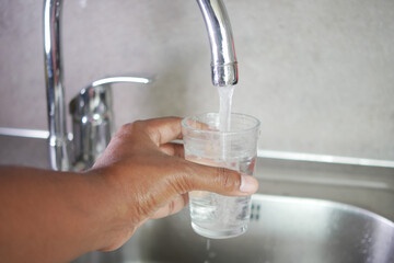  water pouring from a faucet tap in a glass, drinking pure water concept 