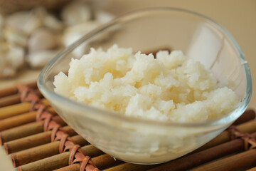 close up of minced garlic on a wooden spoon 