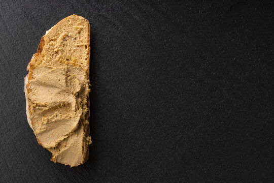 liver pate  spread on the bread fuagra chicken pate closeup space for text sand wich in the hand salt and pepper behaind