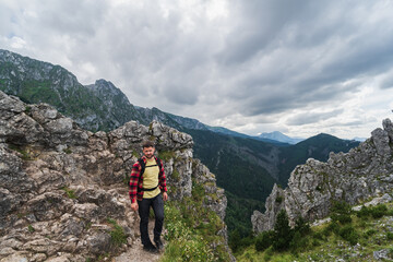 Fototapeta na wymiar A male traveler with a briefcase behind his back high in the Polish Tatra Mountains in summer.