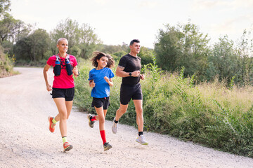 family practicing trail running in the countryside, concept of sport in nature with kids and...