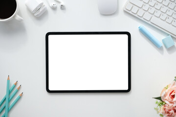 The top view image of white workspace is surrounding by a white blank screen tablet and various...