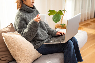 リビングのソファーでパソコン作業をする女性