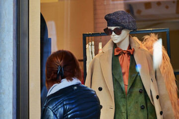 female mannequins appear to peer at passers-by from the window of a clothing store - obrazy, fototapety, plakaty
