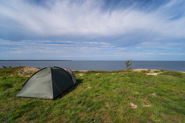 Wild camping in nature.  A tent set up on the steep shore of the Baltic Sea in summer.