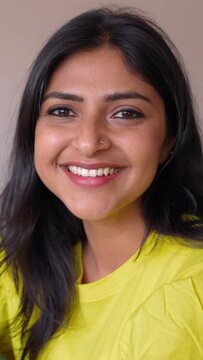 Portrait of happy young indian woman smile at camera sitting on sofa at home. Cheerful head shot of millennial female native of India relaxing on couch. Real ethnic people. Vertical aspect video 9:16